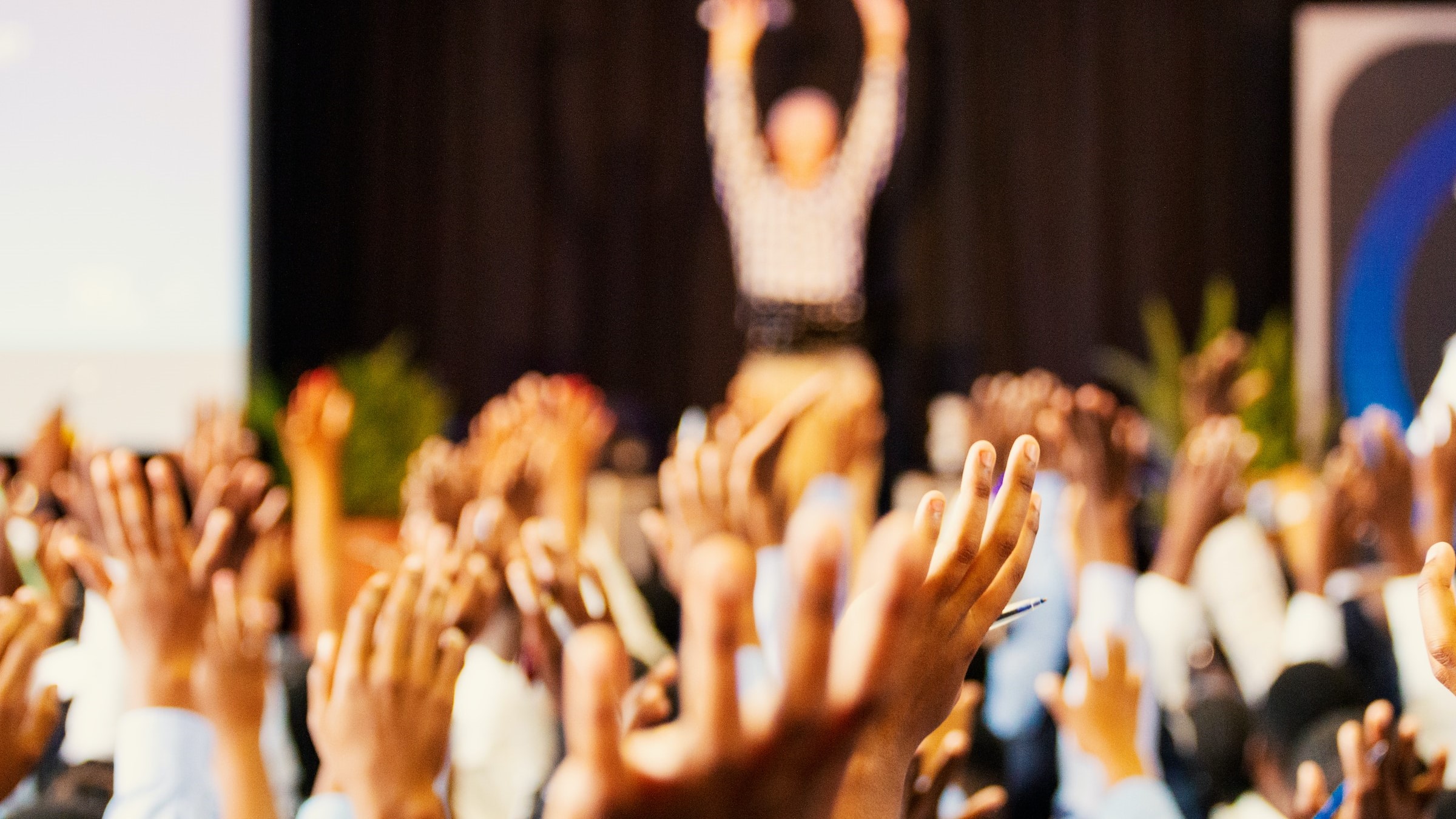 a crowd at a conference with raised hands